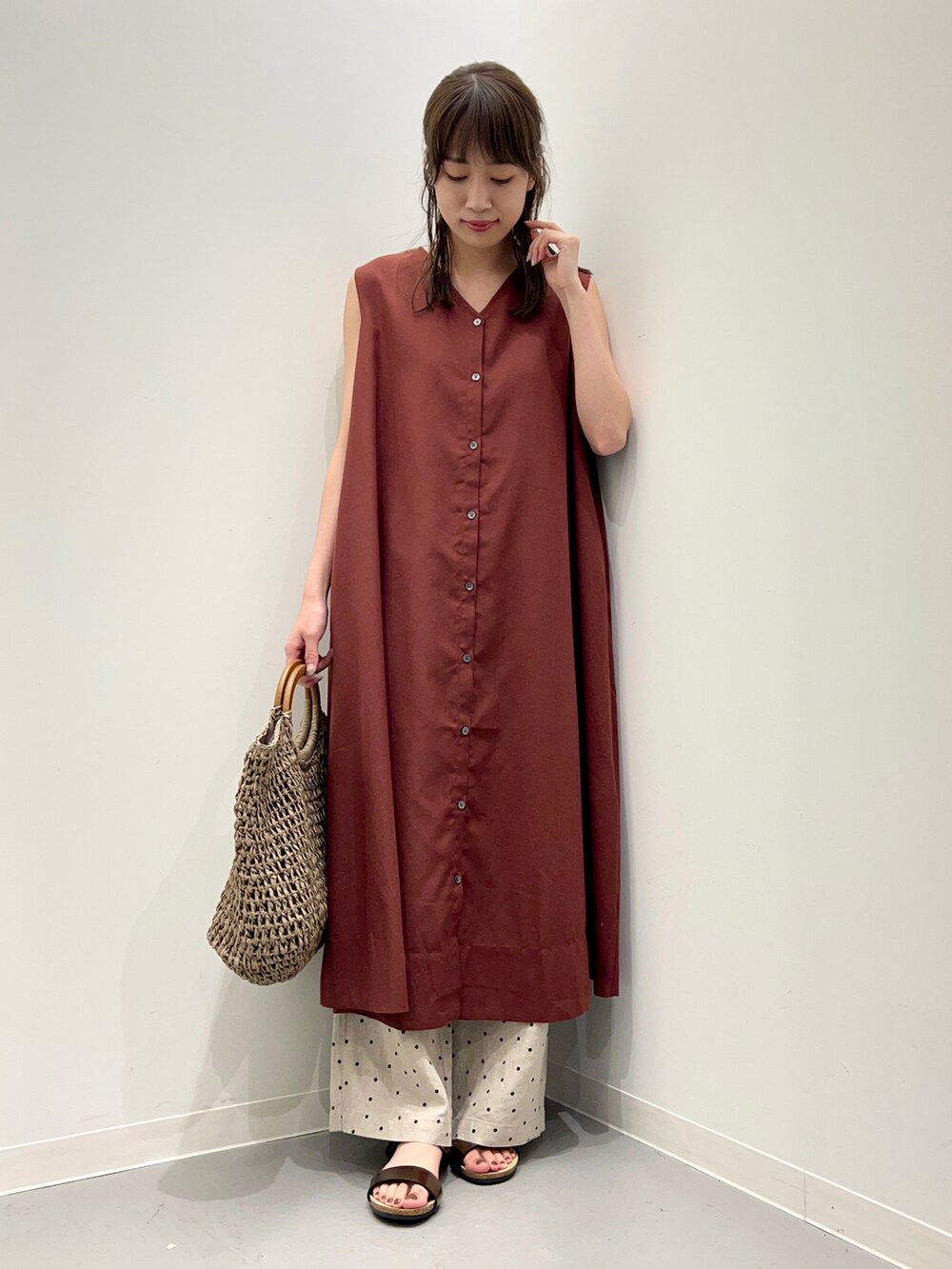 グレー系のトートバッグ、ブラウン系のサンダル、ベージュ系のその他パンツを着用したレディースの夏コーディネートの2枚目の写真