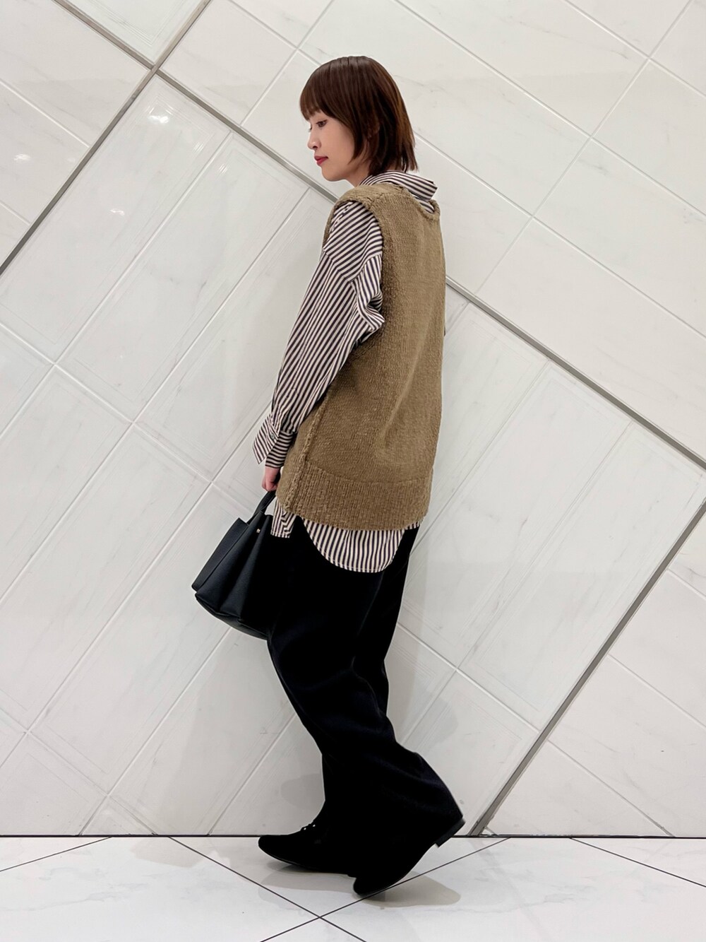 グリーン系のベスト、グレー系のシャツ/ブラウス、ブラック系のその他パンツを着用したレディースの秋コーディネートの2枚目の写真