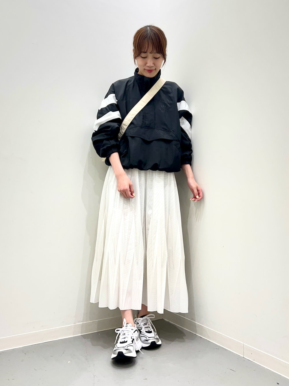 ホワイト系のスニーカー、ホワイト系のスカート、ブラック系のトップスを着用したレディースの春コーディネートの2枚目の写真