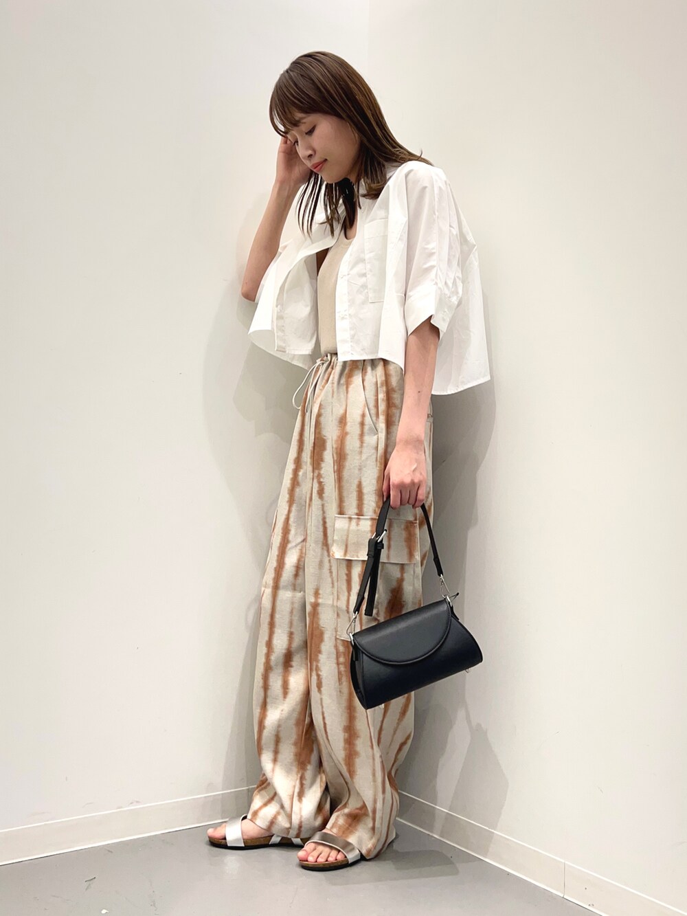 ブラック系のショルダーバッグ、シルバー系のサンダル、ブラウン系のカーゴパンツを着用したレディースの春コーディネートの2枚目の写真