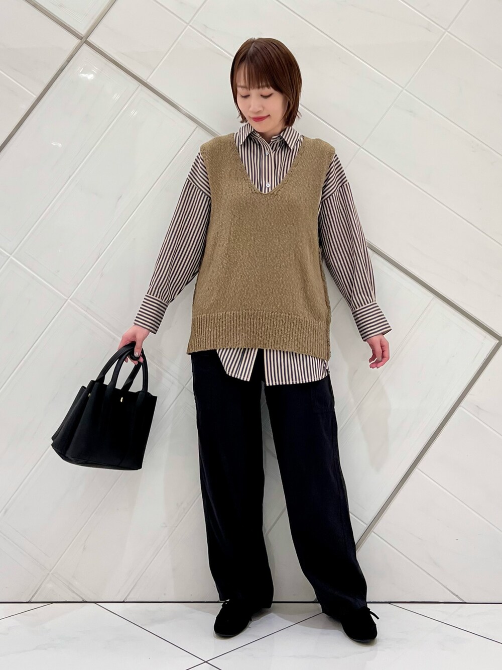 グリーン系のベスト、グレー系のシャツ/ブラウス、ブラック系のその他パンツを着用したレディースの秋コーディネートの4枚目の写真