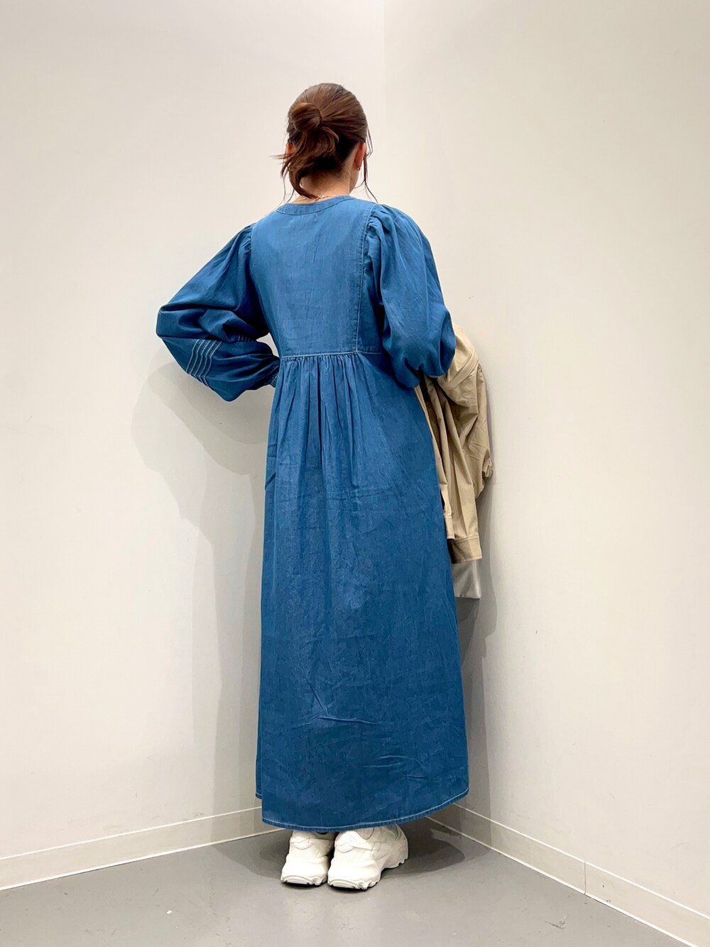 ホワイト系のトートバッグ、ベージュ系のマウンテンパーカー、ブルー系のワンピースを着用したレディースの冬コーディネートの3枚目の写真