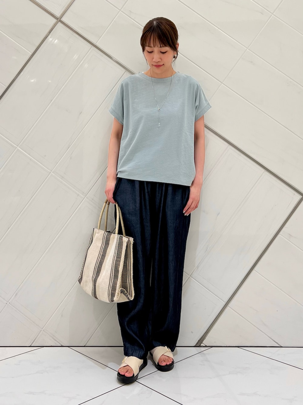 グリーン系のTシャツ/カットソー、ブルー系のデニムパンツ、ホワイト系のトートバッグを着用したレディースの夏コーディネートの4枚目の写真