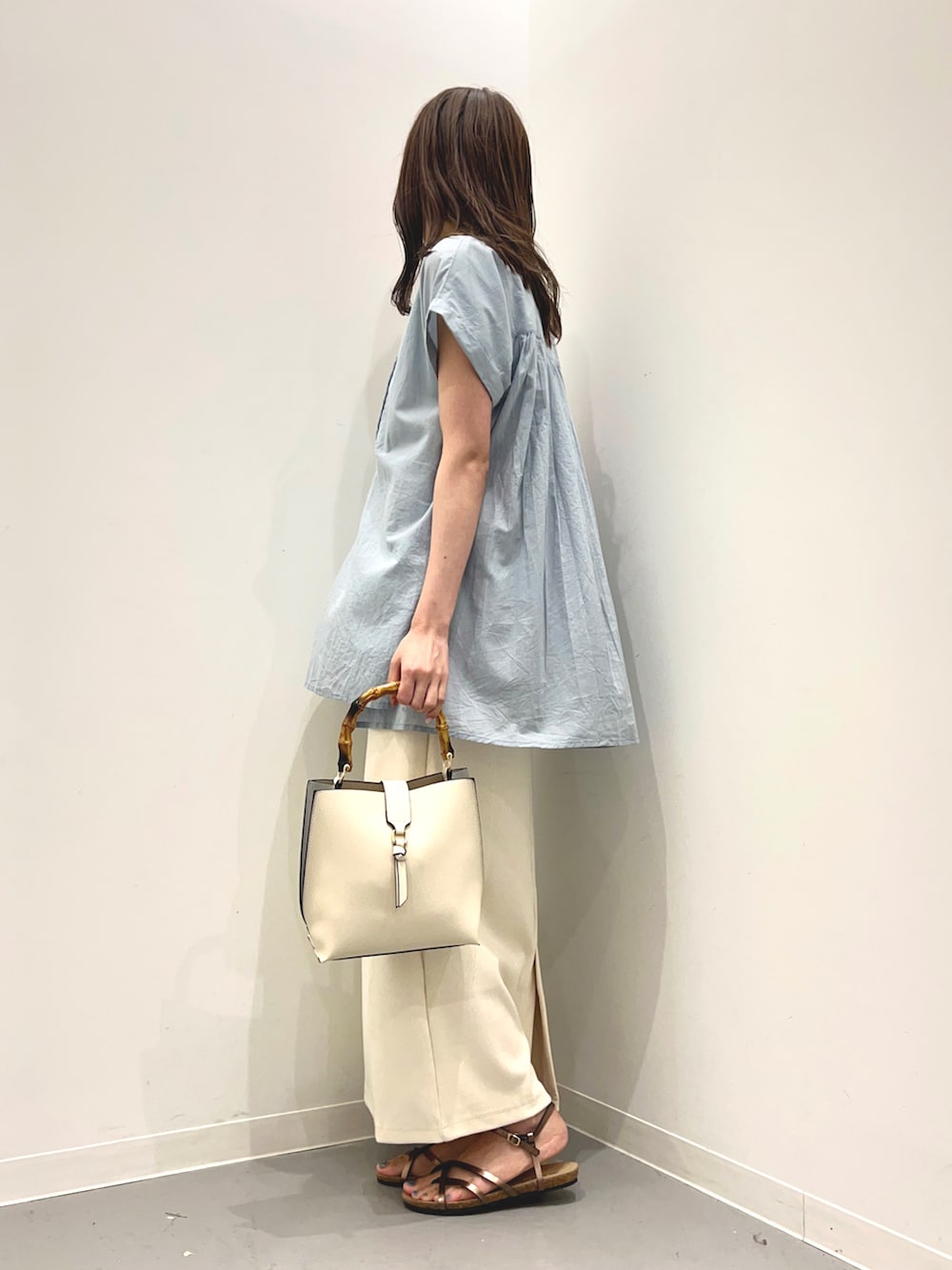 ブルー系のシャツ/ブラウス、ホワイト系のハンドバッグ、ブラウン系のサンダルを着用したレディースの夏コーディネートの2枚目の写真