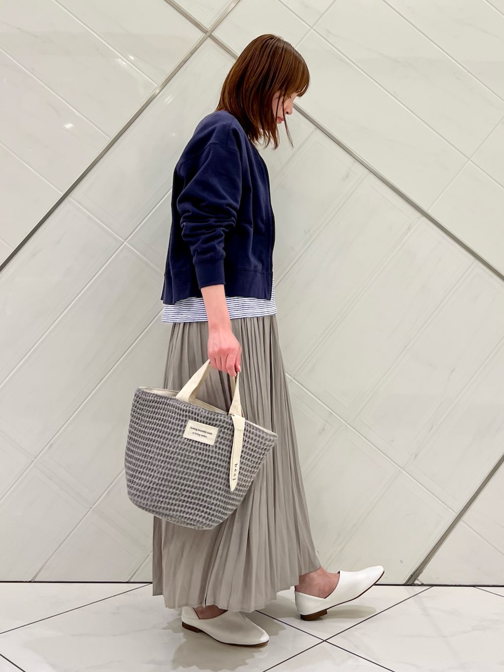 ブルー系のカーディガン/ボレロ、ホワイト系のTシャツ/カットソー、ベージュ系のスカートを着用したレディースの春コーディネートの2枚目の写真