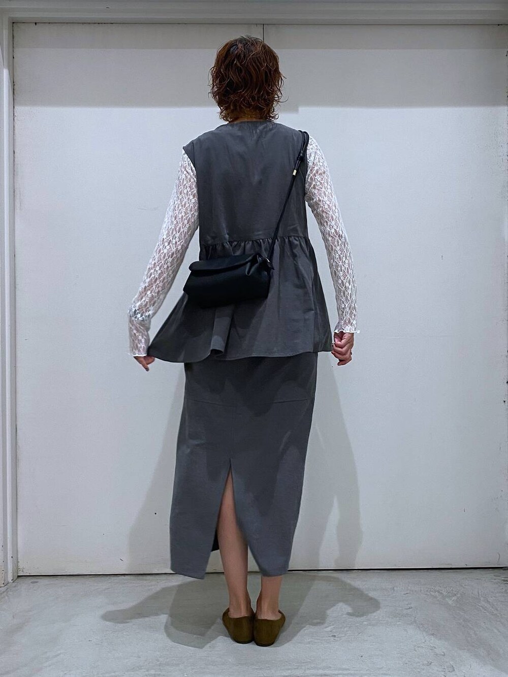 ブラック系のショルダーバッグ、ブラック系のスカート、ブラック系のベストを着用したレディースの秋コーディネートの3枚目の写真