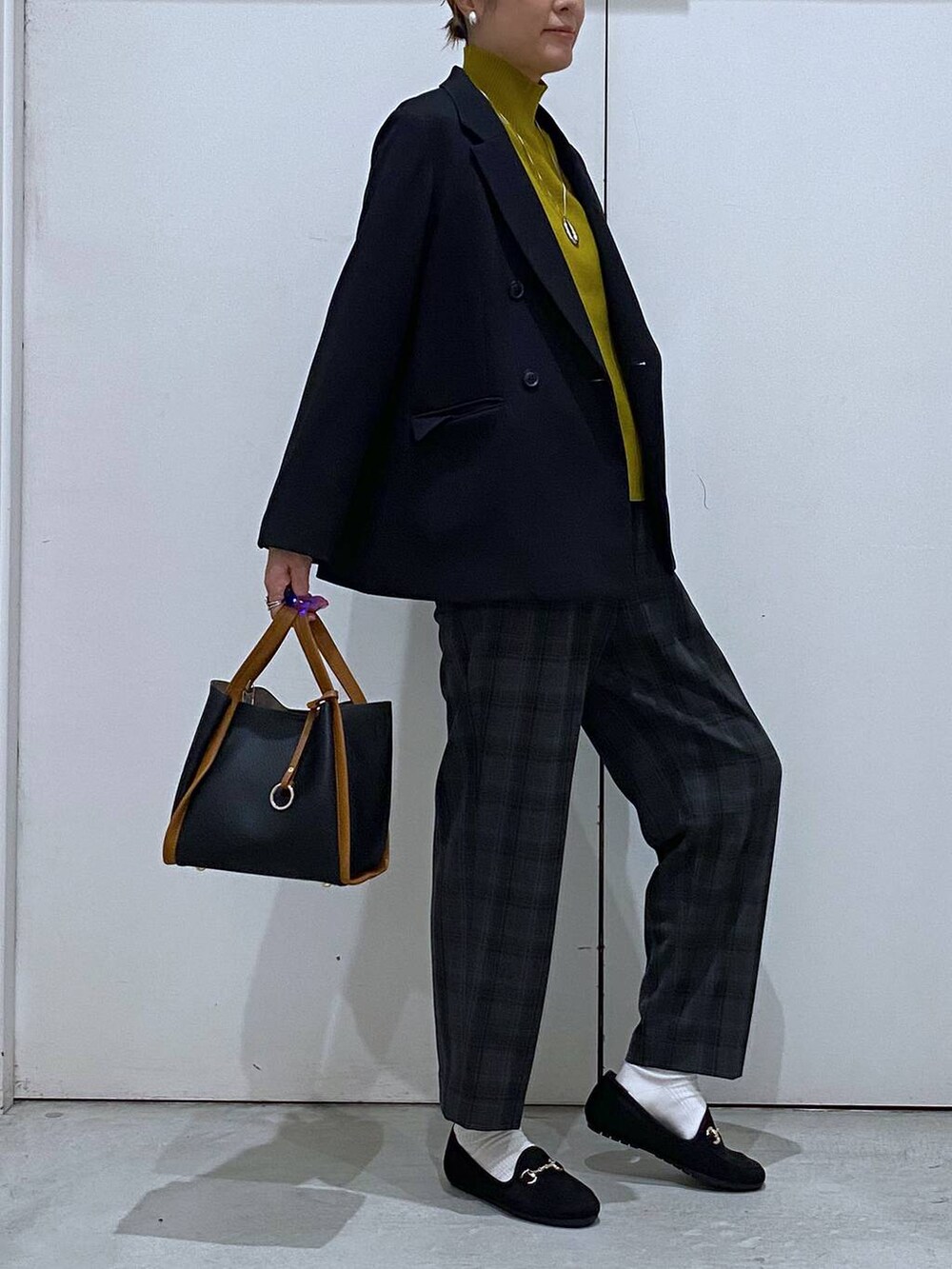 ブラック系のトートバッグ、イエロー系のニット/セーター、ブラック系のテーラードジャケットを着用したレディースの秋コーディネートの5枚目の写真