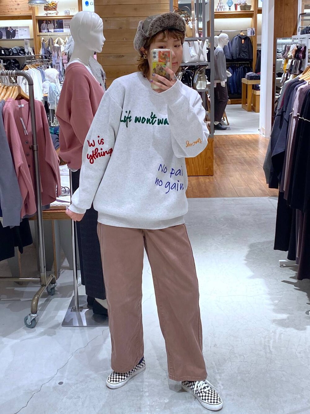 ブラウン系のデニムパンツ、グレー系のニット/セーター、グリーン系のキャップを着用したレディースの秋コーディネートの2枚目の写真