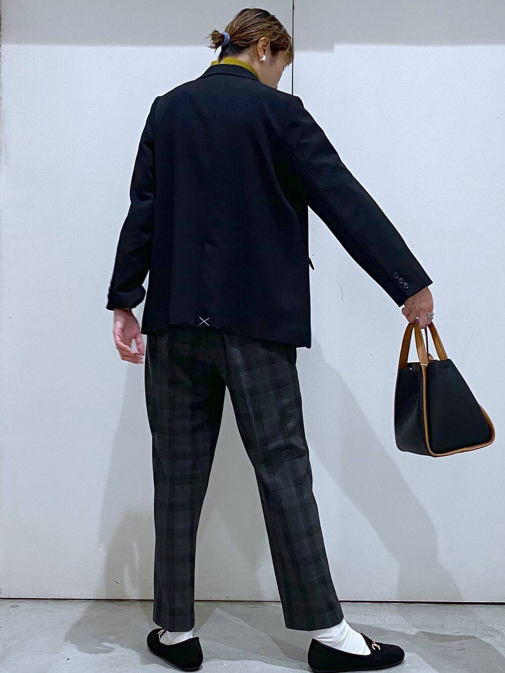 ブラック系のトートバッグ、イエロー系のニット/セーター、ブラック系のテーラードジャケットを着用したレディースの秋コーディネートの4枚目の写真