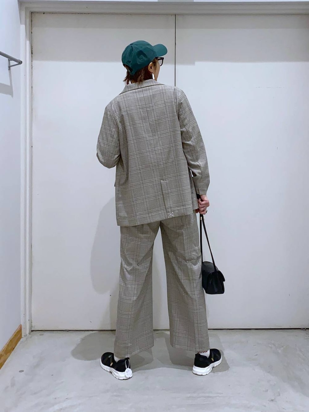 ブラック系のスニーカー、ブラック系のショルダーバッグ、ホワイト系のTシャツ/カットソーを着用したレディースの春コーディネートの3枚目の写真