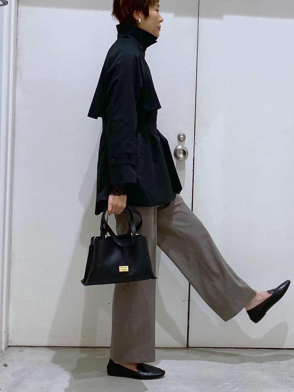 ブラック系のその他シューズ、ブラック系のTシャツ/カットソー、ブラウン系のスラックスを着用したレディースの春コーディネートの5枚目の写真