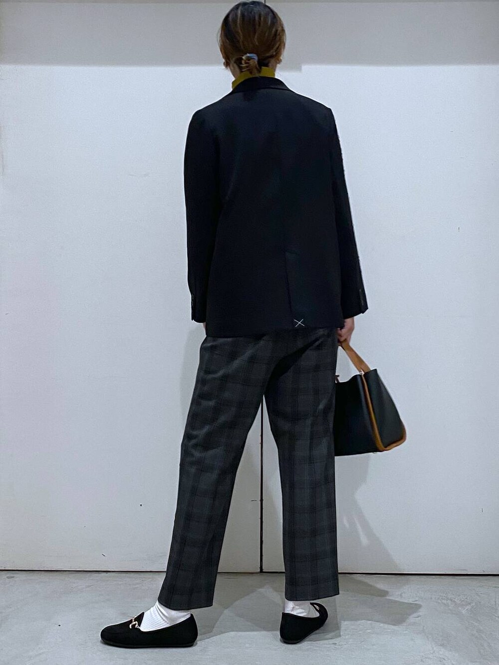 ブラック系のトートバッグ、イエロー系のニット/セーター、ブラック系のテーラードジャケットを着用したレディースの秋コーディネートの3枚目の写真