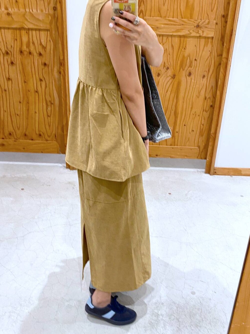 シルバー系のトートバッグ、ブルー系のスニーカー、イエロー系のベストを着用したレディースの夏コーディネートの3枚目の写真