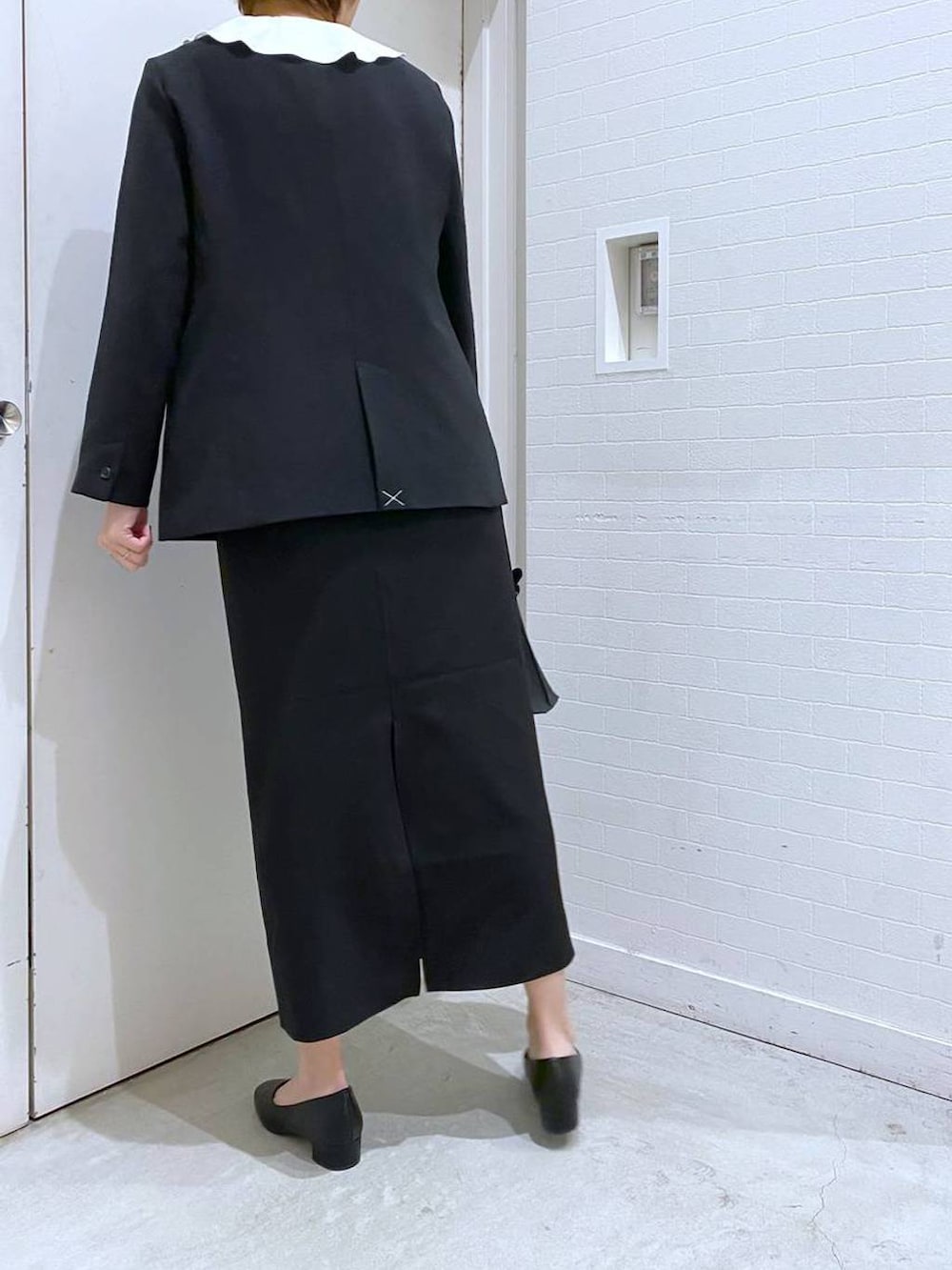 ブラック系のパンプス、ブラック系のスカート、ブラック系のショルダーバッグを着用したレディースの冬コーディネートの3枚目の写真