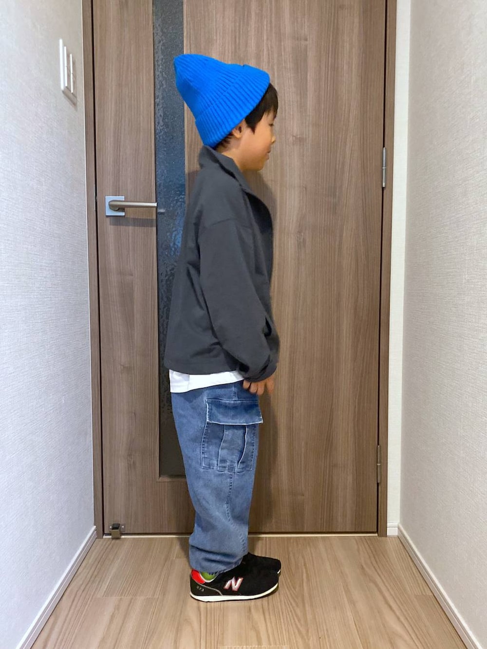 グレー系のブルゾン、ホワイト系のTシャツ/カットソー、ブルー系のデニムパンツを着用したキッズの秋コーディネートの2枚目の写真