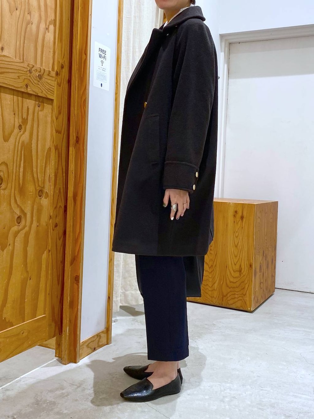 ブラック系のその他シューズ、ブラック系のチェスターコート、ブルー系のその他パンツを着用したレディースの冬コーディネートの2枚目の写真