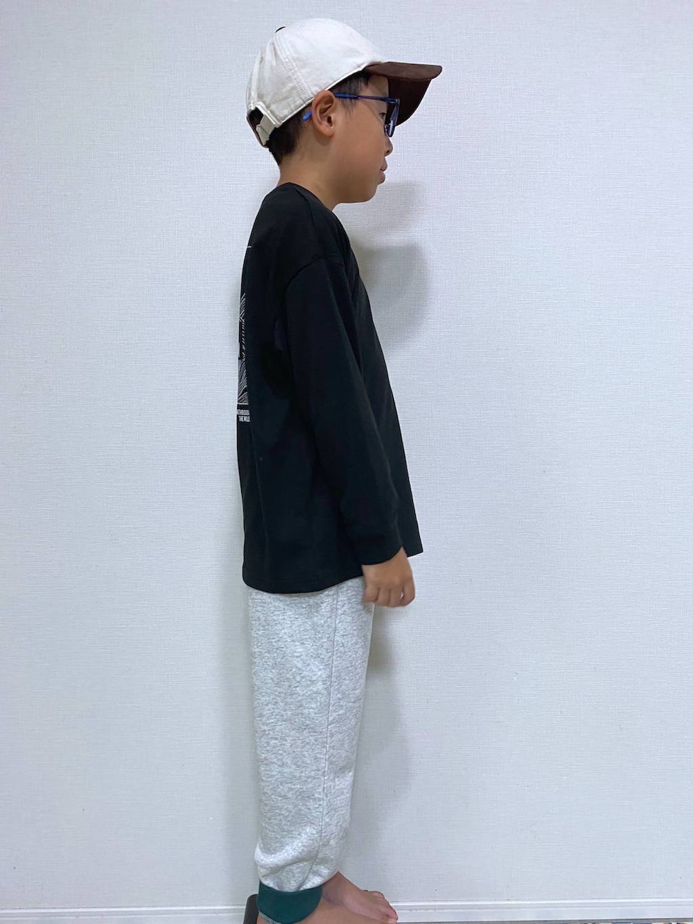 グレー系のスウェットパンツ、ブラック系のTシャツ/カットソー、ベージュ系のキャップを着用したキッズの秋コーディネートの2枚目の写真
