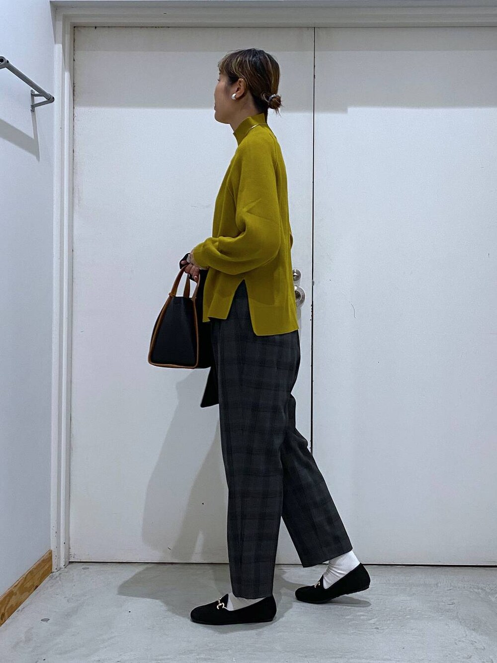 ブラック系のトートバッグ、イエロー系のニット/セーター、ブラック系のテーラードジャケットを着用したレディースの秋コーディネートの7枚目の写真