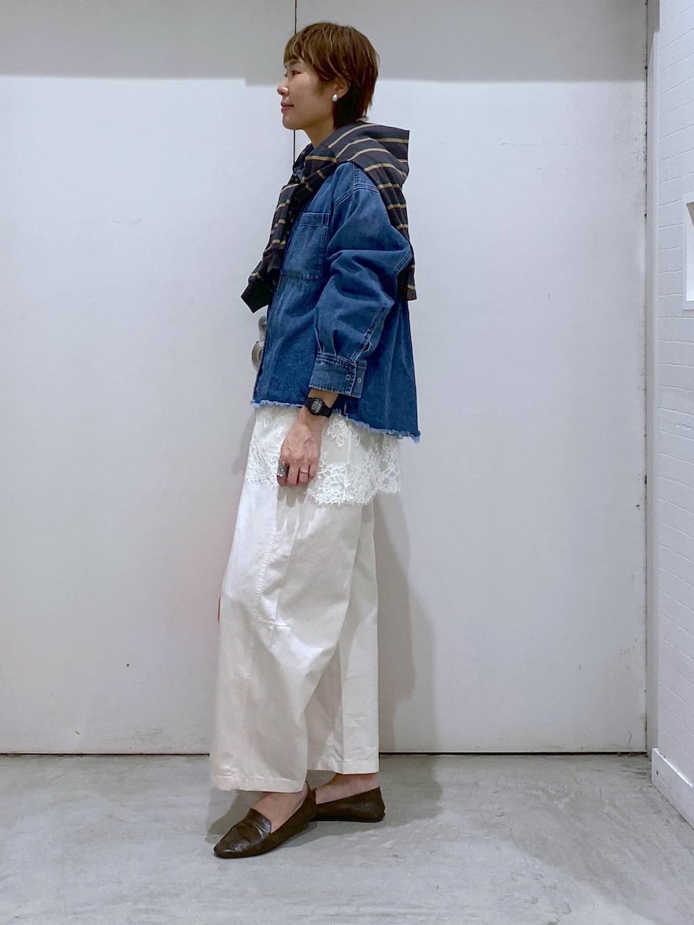 オレンジ系のバックパック/リュック、ブルー系のシャツ/ブラウス、グレー系のTシャツ/カットソーを着用したレディースの春コーディネートの2枚目の写真