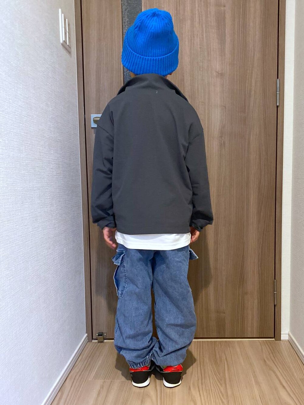 グレー系のブルゾン、ホワイト系のTシャツ/カットソー、ブルー系のデニムパンツを着用したキッズの秋コーディネートの3枚目の写真