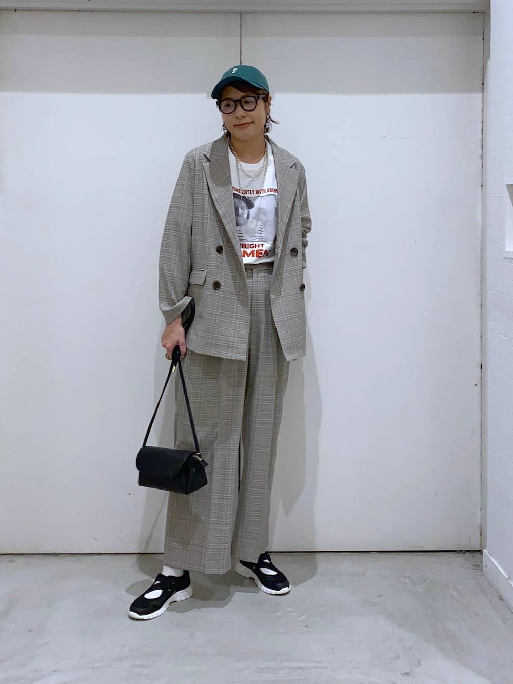 ブラック系のスニーカー、ブラック系のショルダーバッグ、ホワイト系のTシャツ/カットソーを着用したレディースの春コーディネートの4枚目の写真