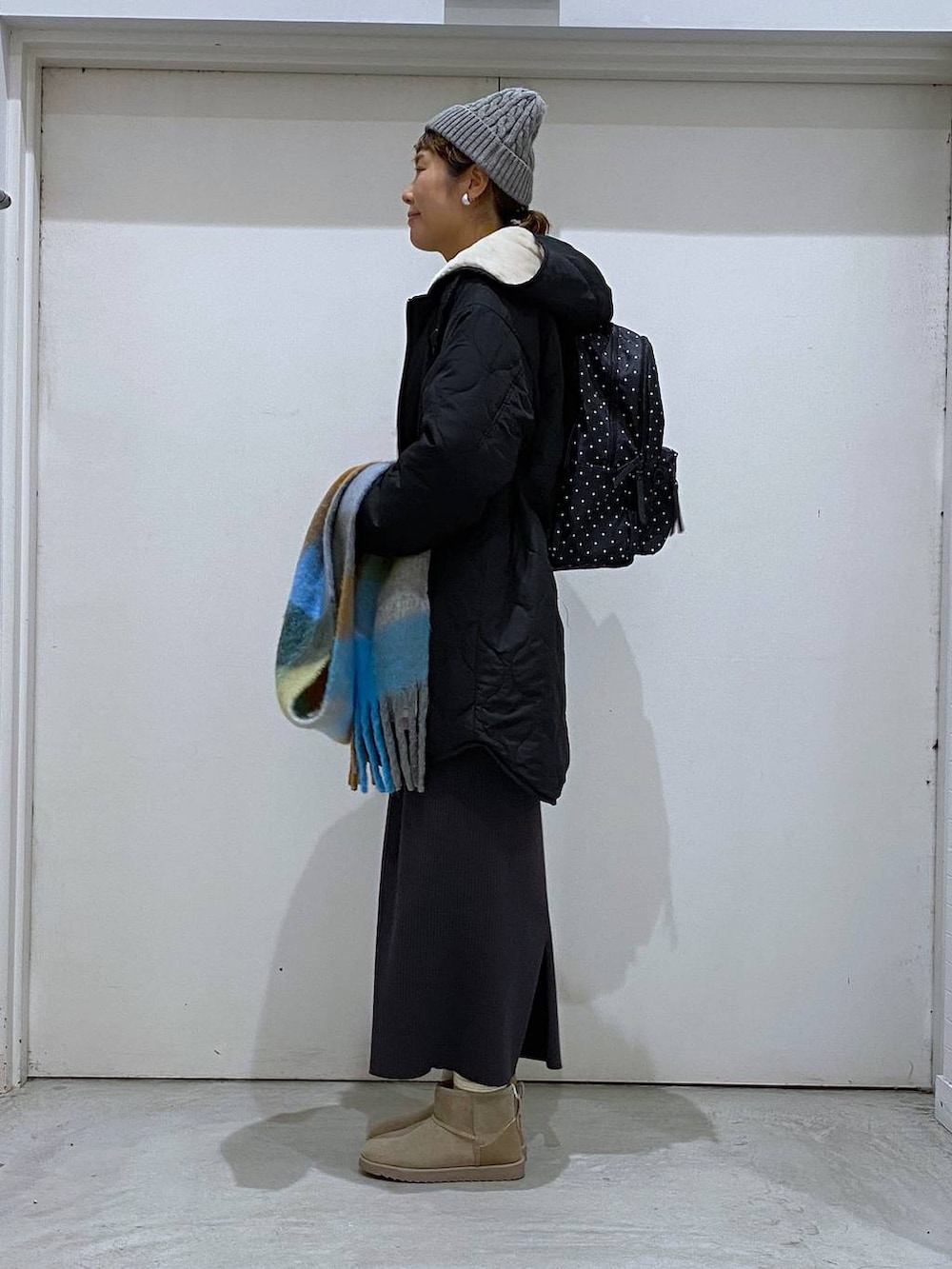 ブラック系のブルゾン、グレー系のバックパック/リュック、グレー系のワンピースを着用したレディースの冬コーディネートの2枚目の写真