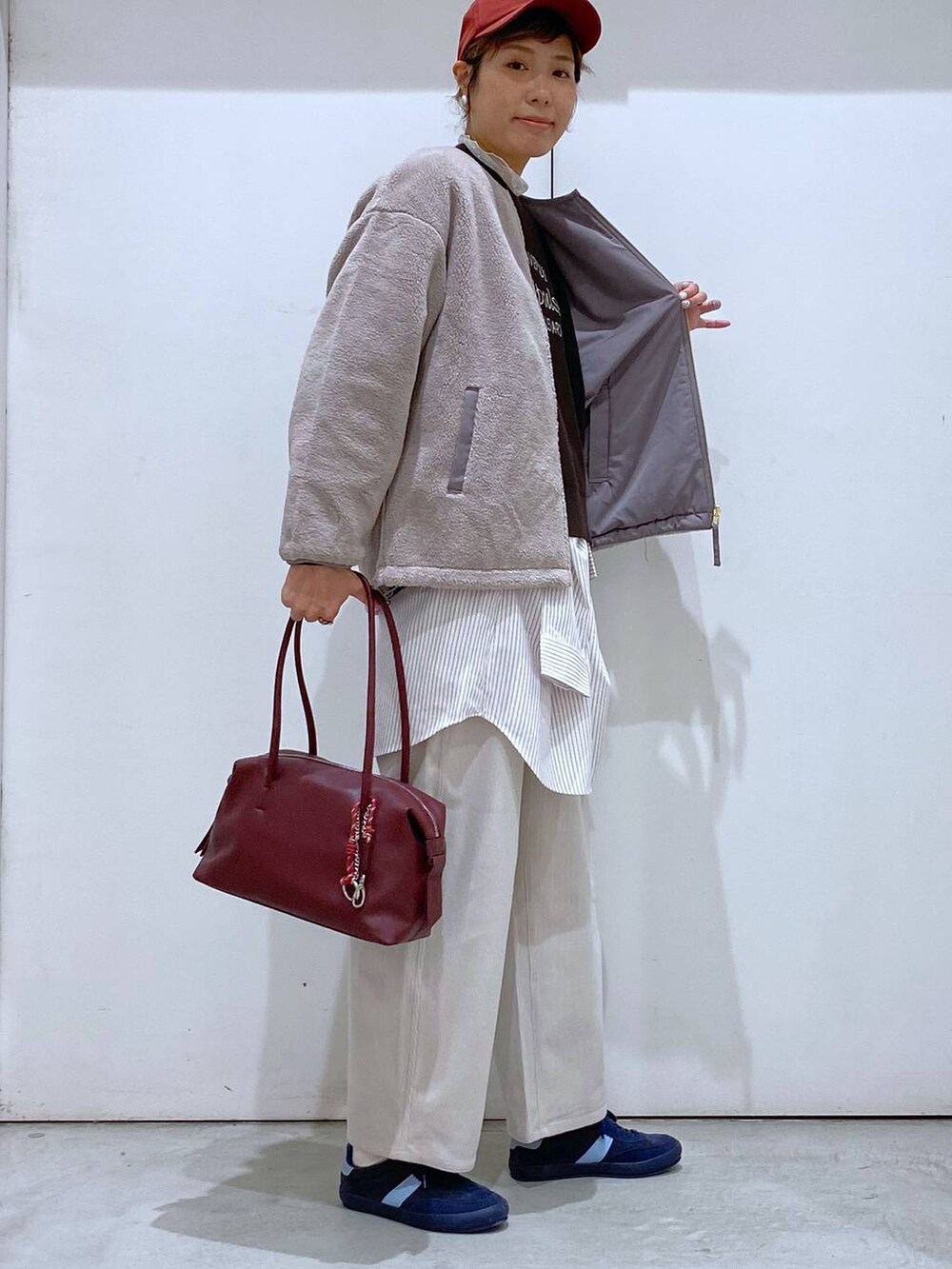 ブルー系のスニーカー、レッド系のボストンバッグ、ブラウン系のブルゾンを着用したレディースの秋コーディネートの2枚目の写真