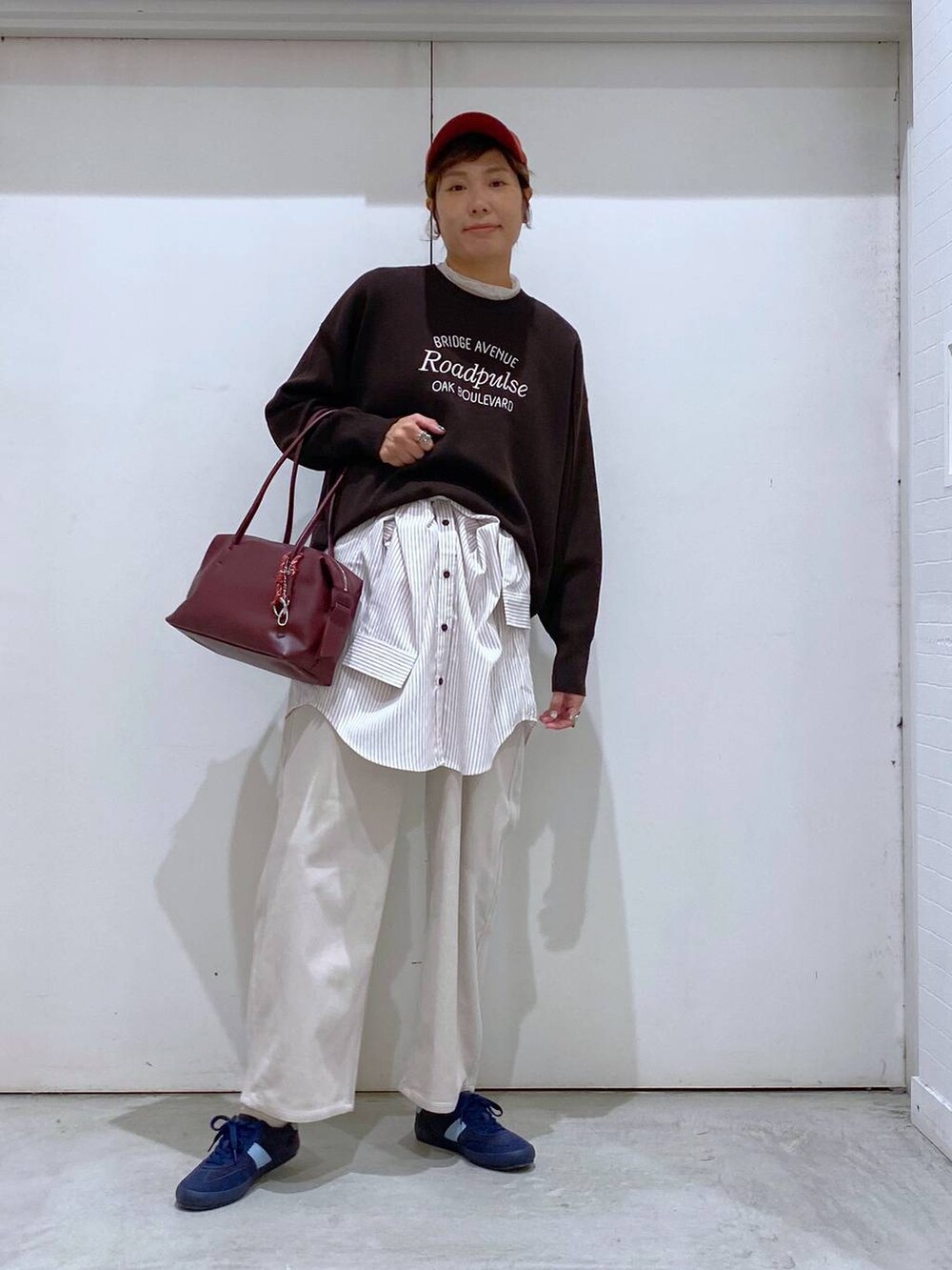 ブルー系のスニーカー、レッド系のボストンバッグ、ブラウン系のブルゾンを着用したレディースの秋コーディネートの3枚目の写真