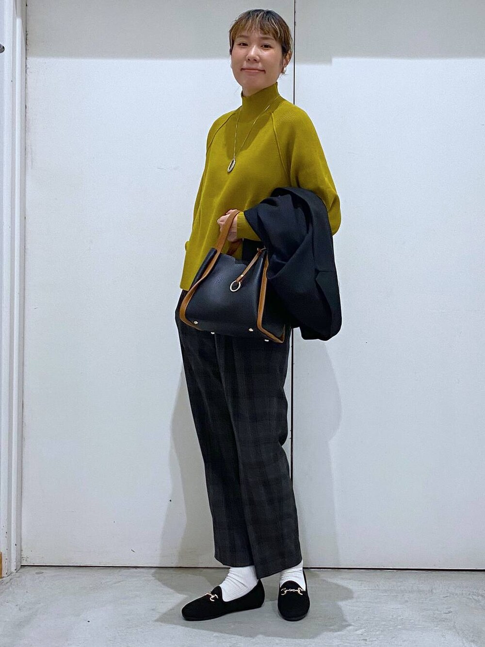 ブラック系のトートバッグ、イエロー系のニット/セーター、ブラック系のテーラードジャケットを着用したレディースの秋コーディネートの6枚目の写真