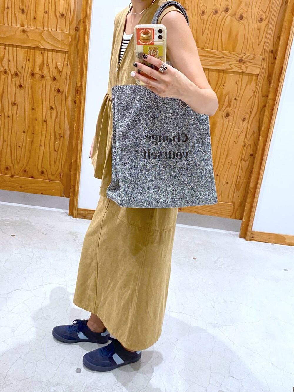 シルバー系のトートバッグ、ブルー系のスニーカー、イエロー系のベストを着用したレディースの夏コーディネートの2枚目の写真