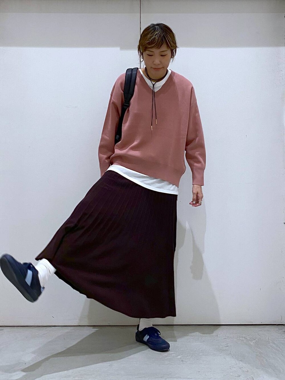 ブルー系のスニーカー、ピンク系のスウェット、ブラウン系のスカートを着用したレディースの秋コーディネートの5枚目の写真