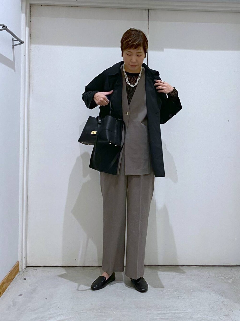 ブラック系のその他シューズ、ブラック系のTシャツ/カットソー、ブラウン系のスラックスを着用したレディースの春コーディネートの2枚目の写真