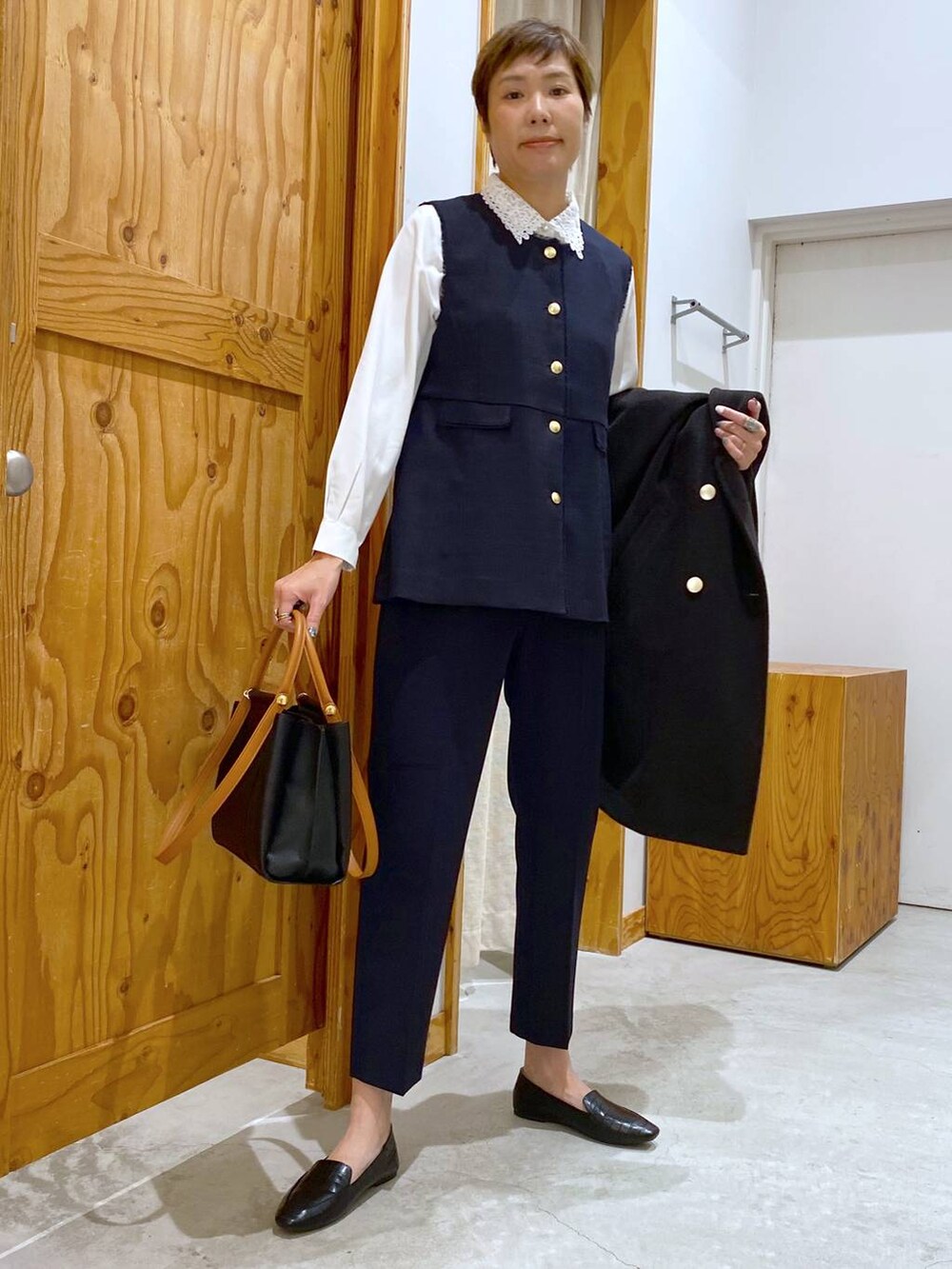 ブラック系のその他シューズ、ブラック系のチェスターコート、ブルー系のその他パンツを着用したレディースの冬コーディネートの4枚目の写真