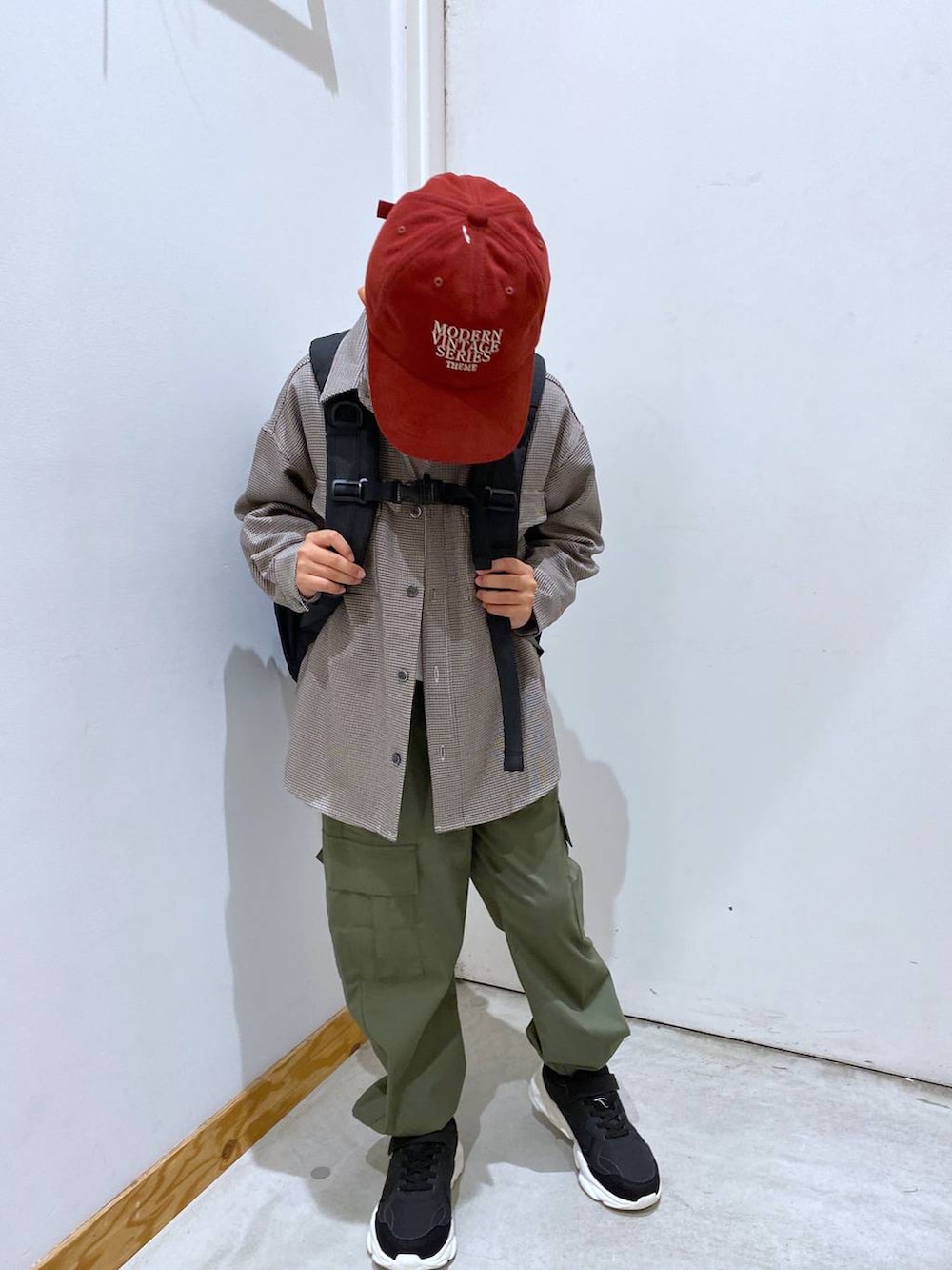 グリーン系のカーゴパンツ、ブラウン系のシャツ/ブラウス、ブラック系のバックパック/リュックを着用したキッズの秋コーディネートの2枚目の写真