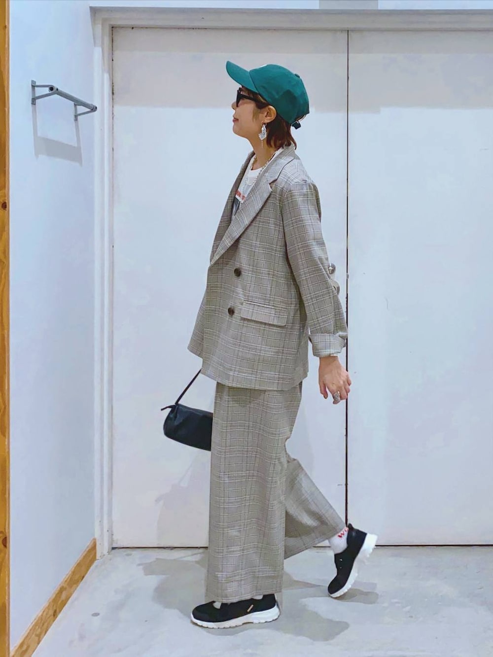 ブラック系のスニーカー、ブラック系のショルダーバッグ、ホワイト系のTシャツ/カットソーを着用したレディースの春コーディネートの2枚目の写真