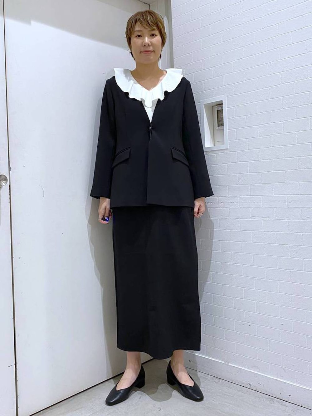 ブラック系のパンプス、ブラック系のスカート、ブラック系のショルダーバッグを着用したレディースの冬コーディネートの5枚目の写真