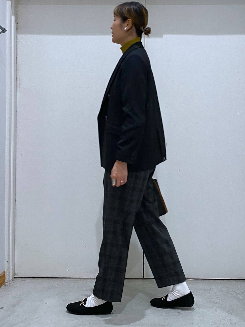 ブラック系のトートバッグ、イエロー系のニット/セーター、ブラック系のテーラードジャケットを着用したレディースの秋コーディネートの2枚目の写真