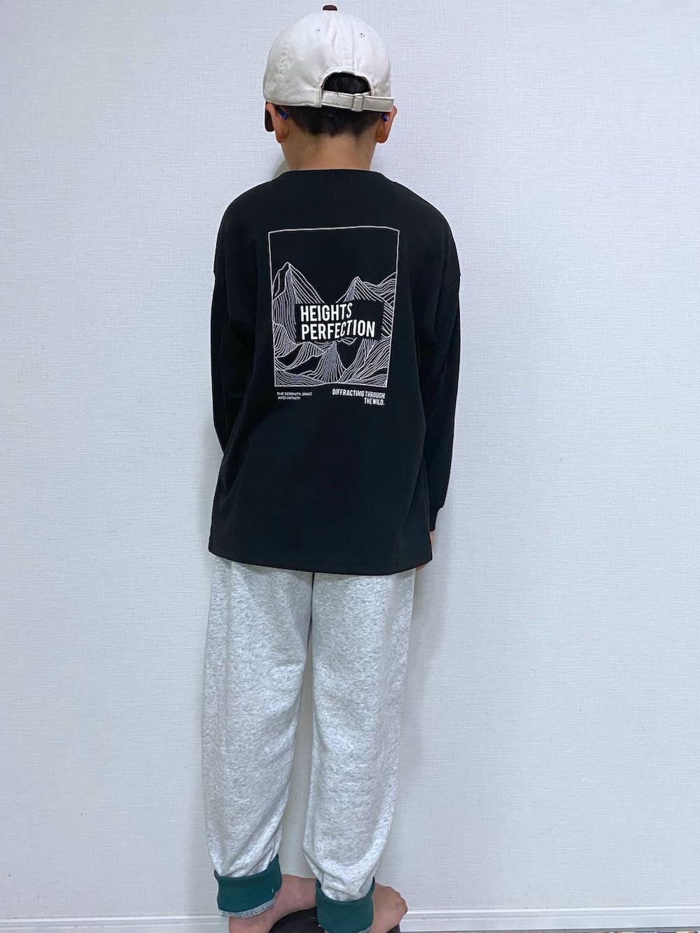 グレー系のスウェットパンツ、ブラック系のTシャツ/カットソー、ベージュ系のキャップを着用したキッズの秋コーディネートの3枚目の写真