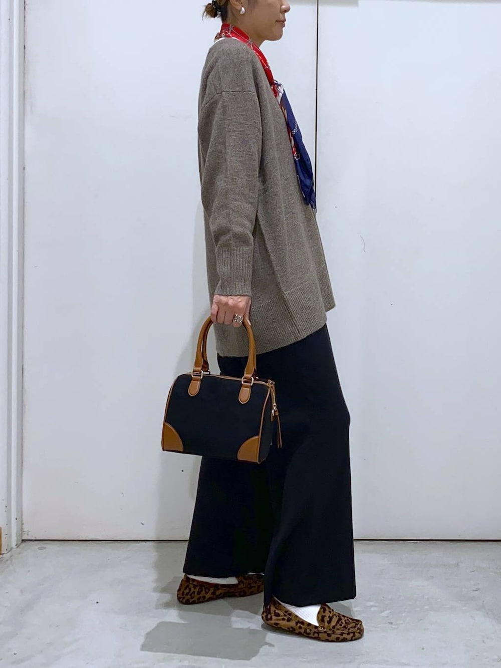 ブラウン系のニット/セーター、ホワイト系のTシャツ/カットソー、ブラック系のボストンバッグを着用したレディースの冬コーディネートの2枚目の写真