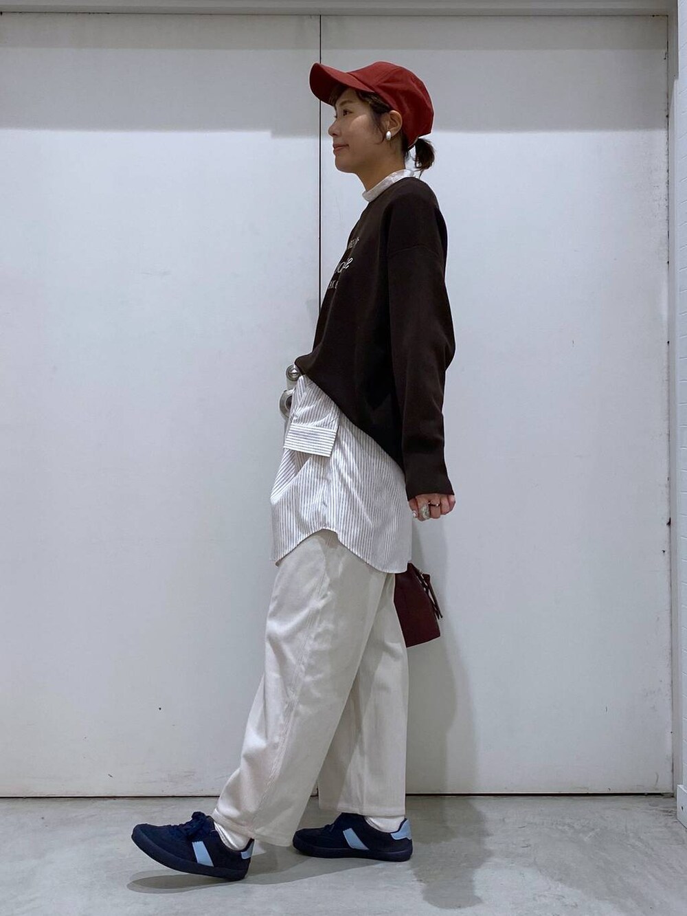 ブルー系のスニーカー、レッド系のボストンバッグ、ブラウン系のブルゾンを着用したレディースの秋コーディネートの4枚目の写真