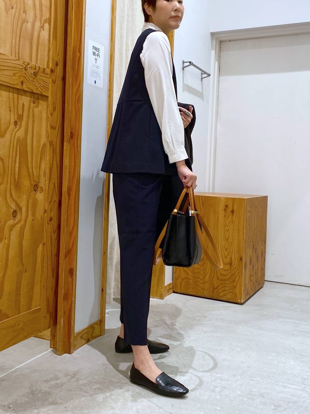 ブラック系のその他シューズ、ブラック系のチェスターコート、ブルー系のその他パンツを着用したレディースの冬コーディネートの7枚目の写真