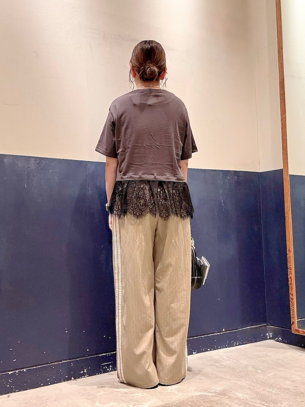 ブラック系のショルダーバッグ、ベージュ系のスラックス、グレー系のTシャツ/カットソーを着用したレディースの夏コーディネートの3枚目の写真