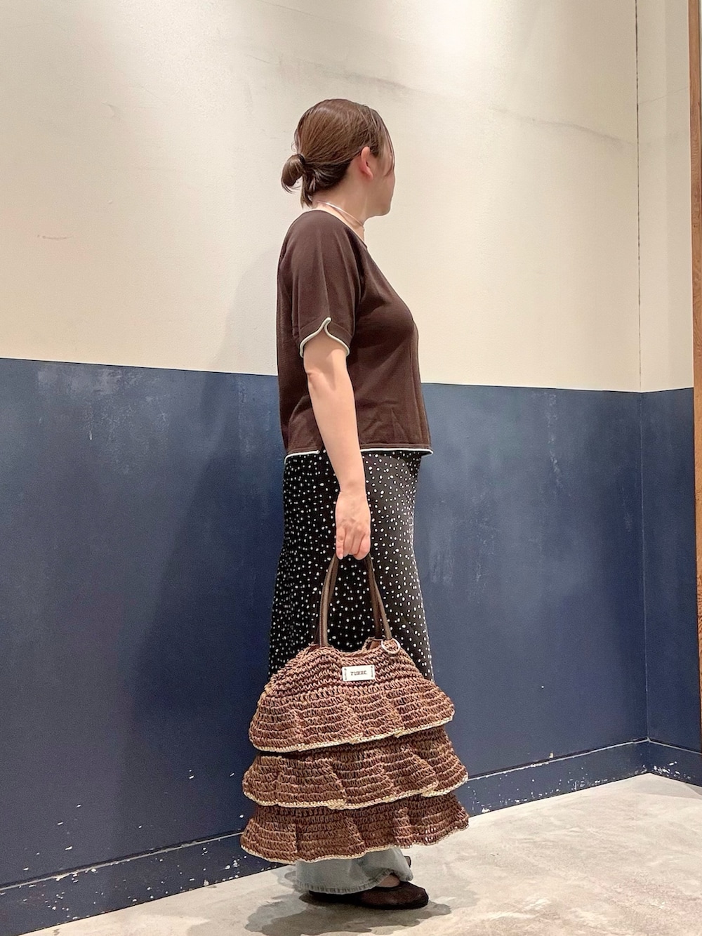 ブラウン系のトートバッグ、ブラック系のパンプス、ブルー系のデニムパンツを着用したレディースの夏コーディネートの2枚目の写真