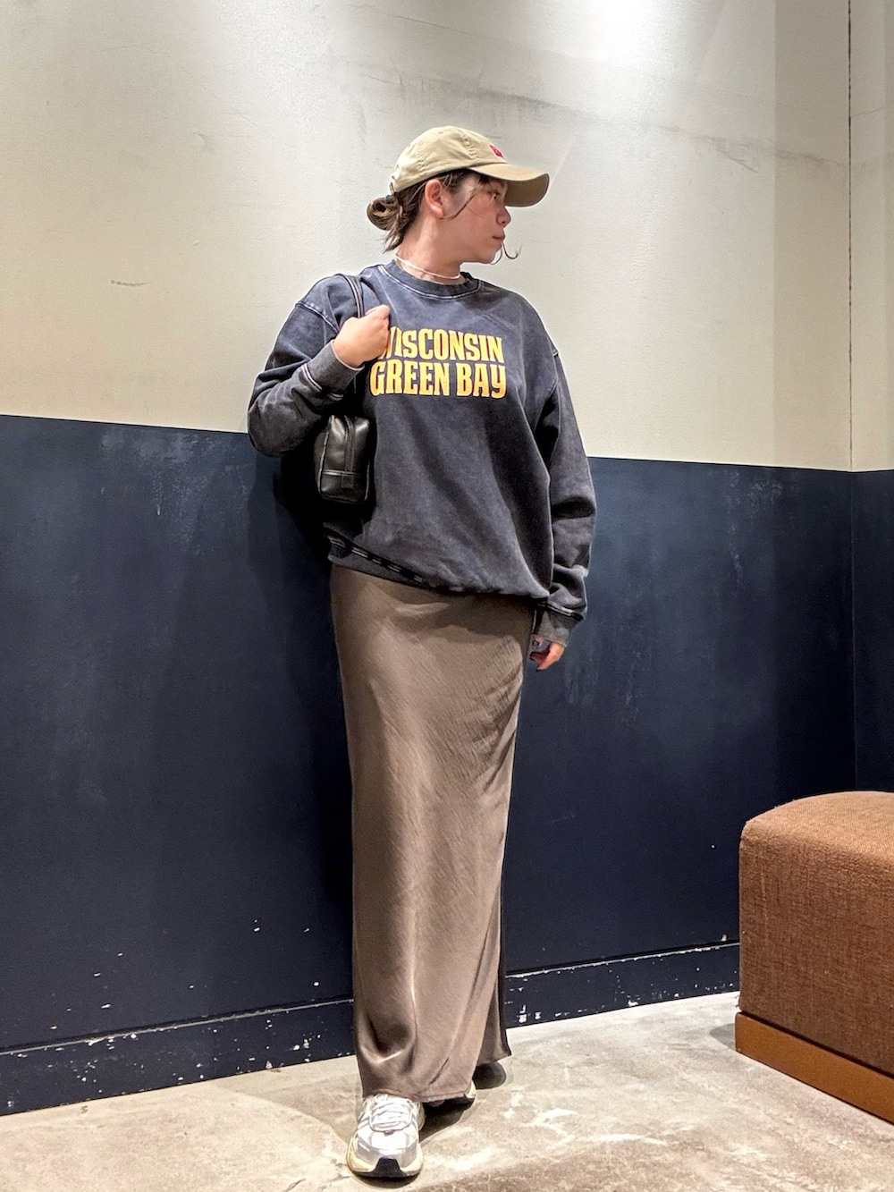 グレー系のスカート、ブラック系のトートバッグ、ブルー系のスウェットを着用したレディースの秋コーディネートの2枚目の写真