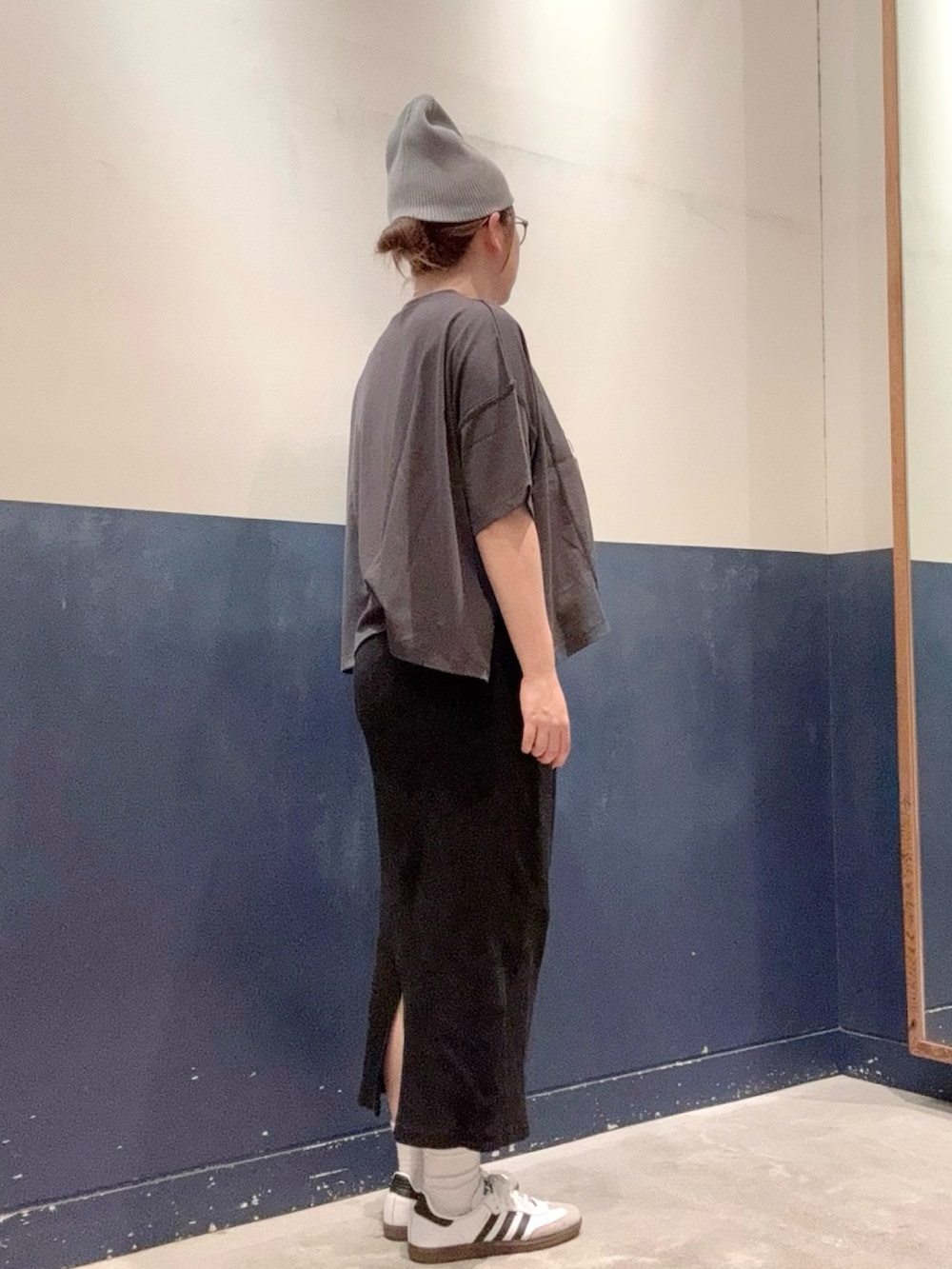 ブラック系のスカート、ブラック系のショルダーバッグ、グレー系のTシャツ/カットソーを着用したレディースの秋コーディネートの2枚目の写真