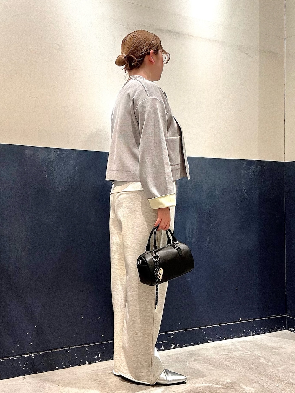 シルバー系のパンプス、ブラック系のショルダーバッグ、ホワイト系のスウェットパンツを着用したレディースの冬コーディネートの2枚目の写真