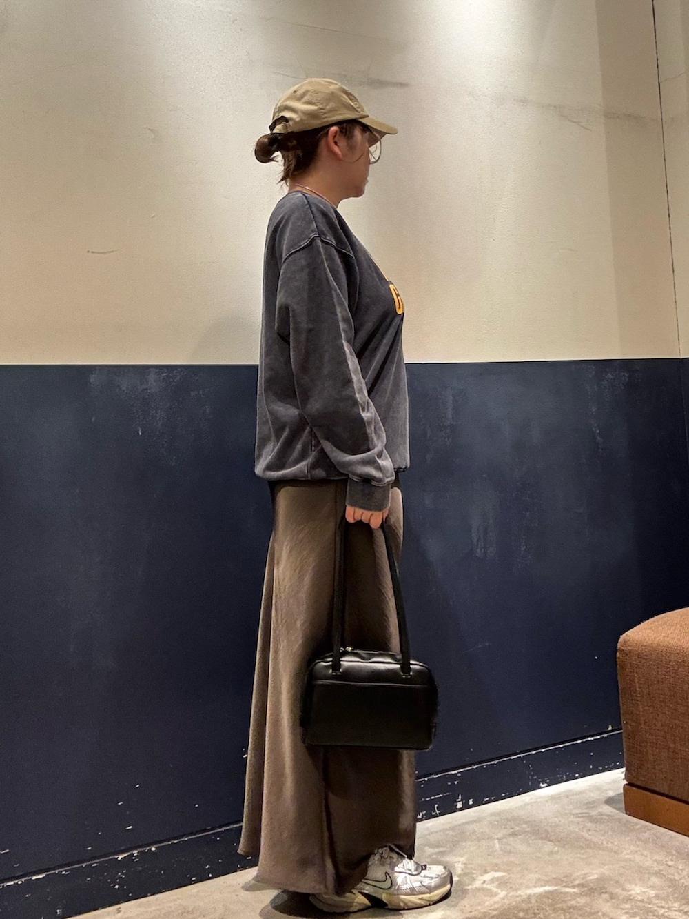 グレー系のスカート、ブラック系のトートバッグ、ブルー系のスウェットを着用したレディースの秋コーディネートの3枚目の写真
