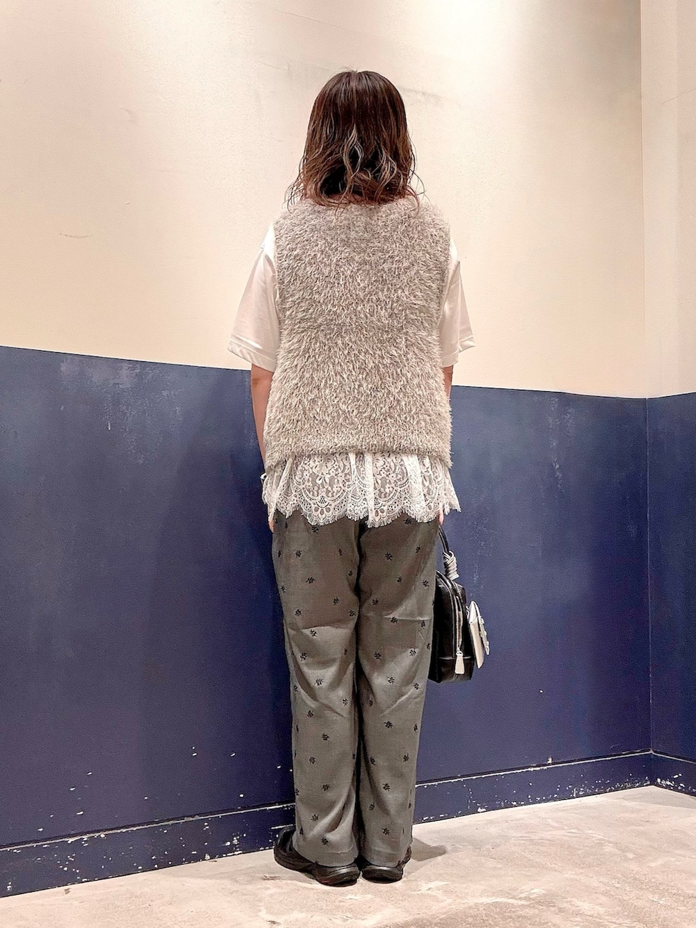 グレー系のスラックス、ブラック系のショルダーバッグ、ホワイト系のTシャツ/カットソーを着用したレディースの夏コーディネートの3枚目の写真