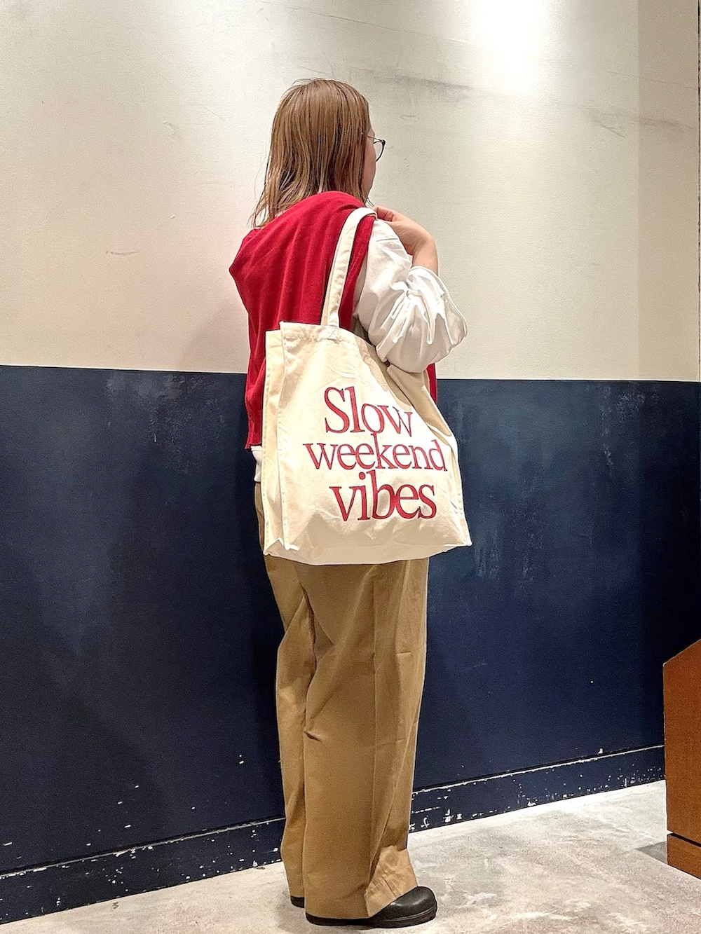 レッド系のニット/セーター、ホワイト系のTシャツ/カットソー、ベージュ系のデニムパンツを着用したレディースの冬コーディネートの2枚目の写真