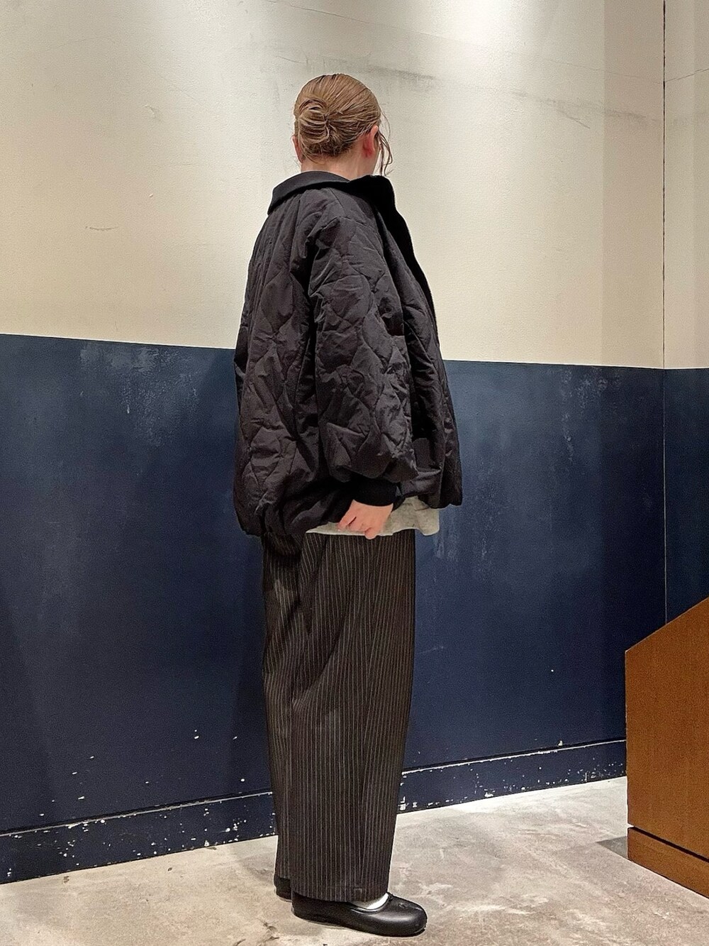 ブラック系のブルゾン、グレー系のスラックス、ホワイト系のニット/セーターを着用したレディースの冬コーディネートの2枚目の写真